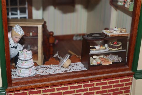 A group of three dolls house models of shops with figures and accessories and an unfinished dolls house